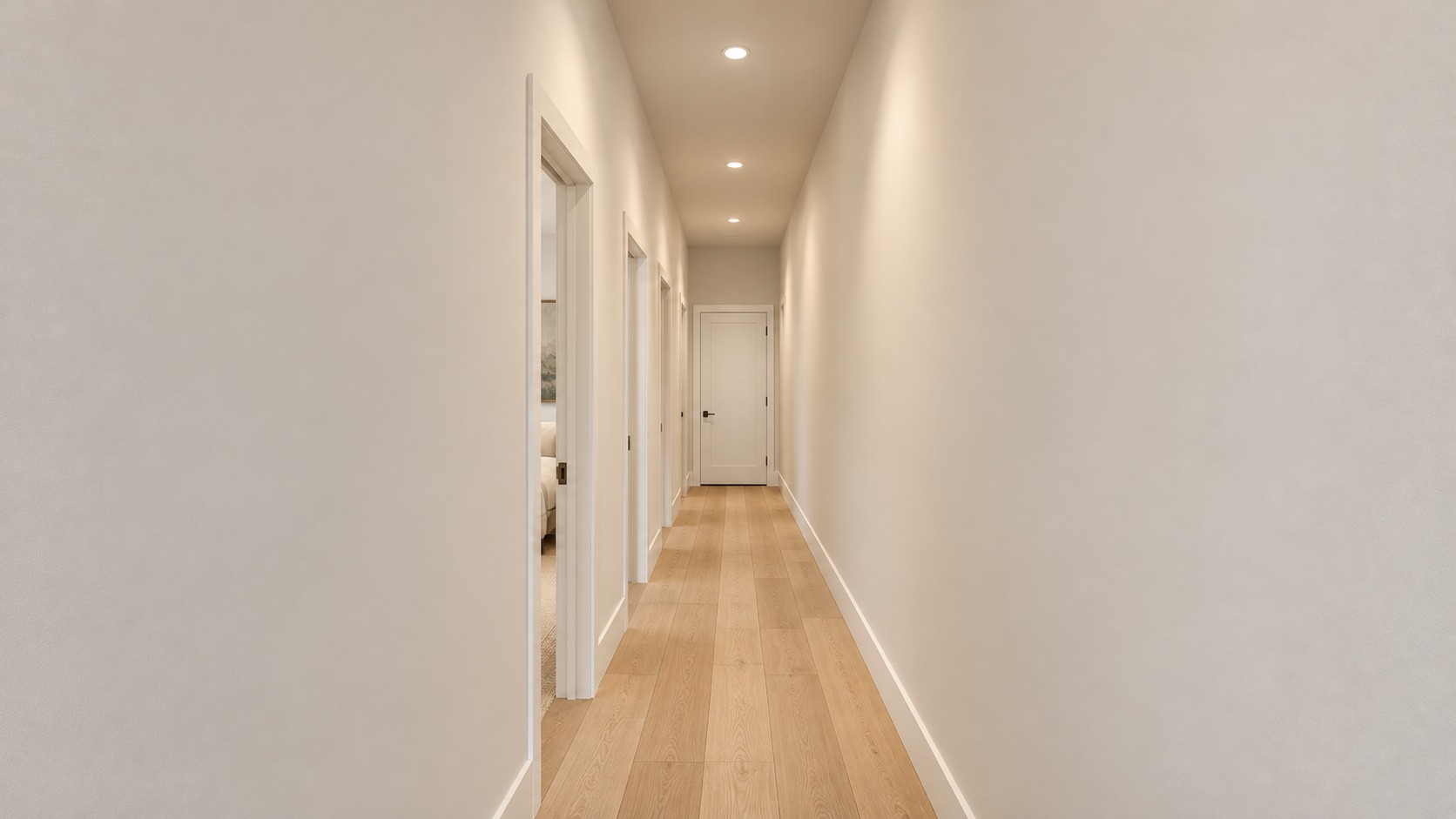 Narrow residential hallway with white door frames, oak floor and recessed lighting